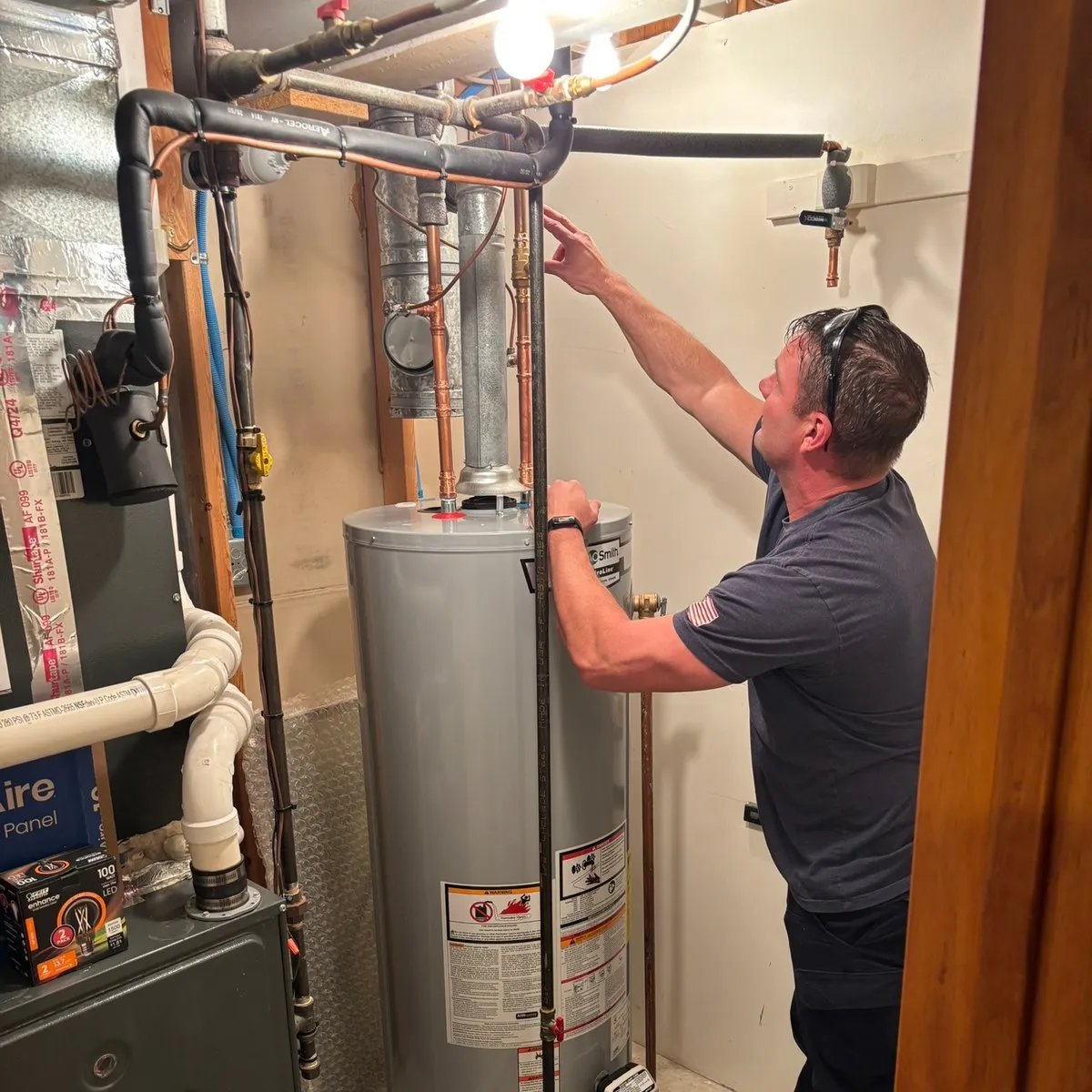 Mike Livingston, Christopherson Mechanical technician, working on copper supply lines above an A.O. Smith water heater in a finished basement.